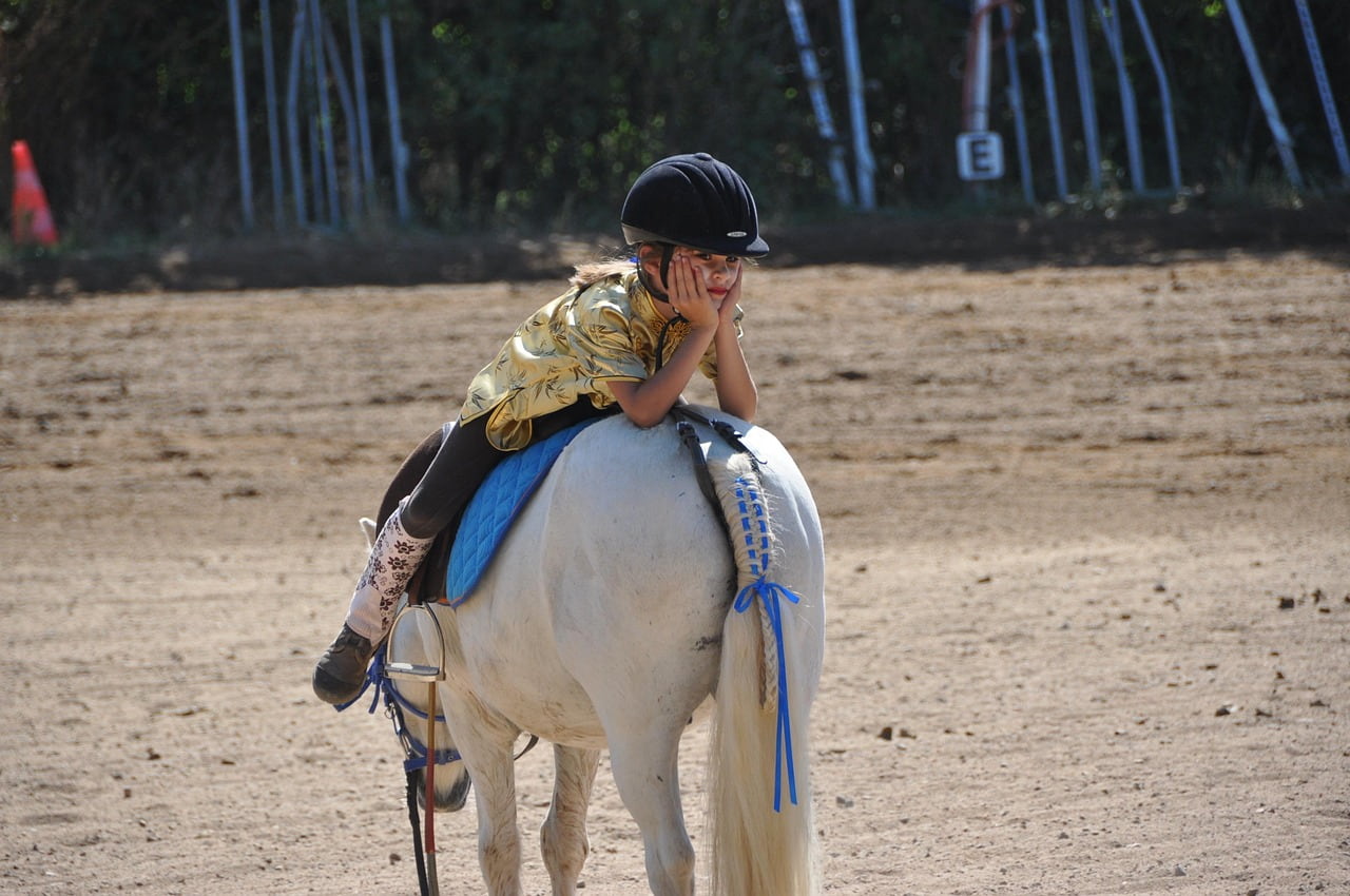 Ein Kind liegt auf einem Reitpferd