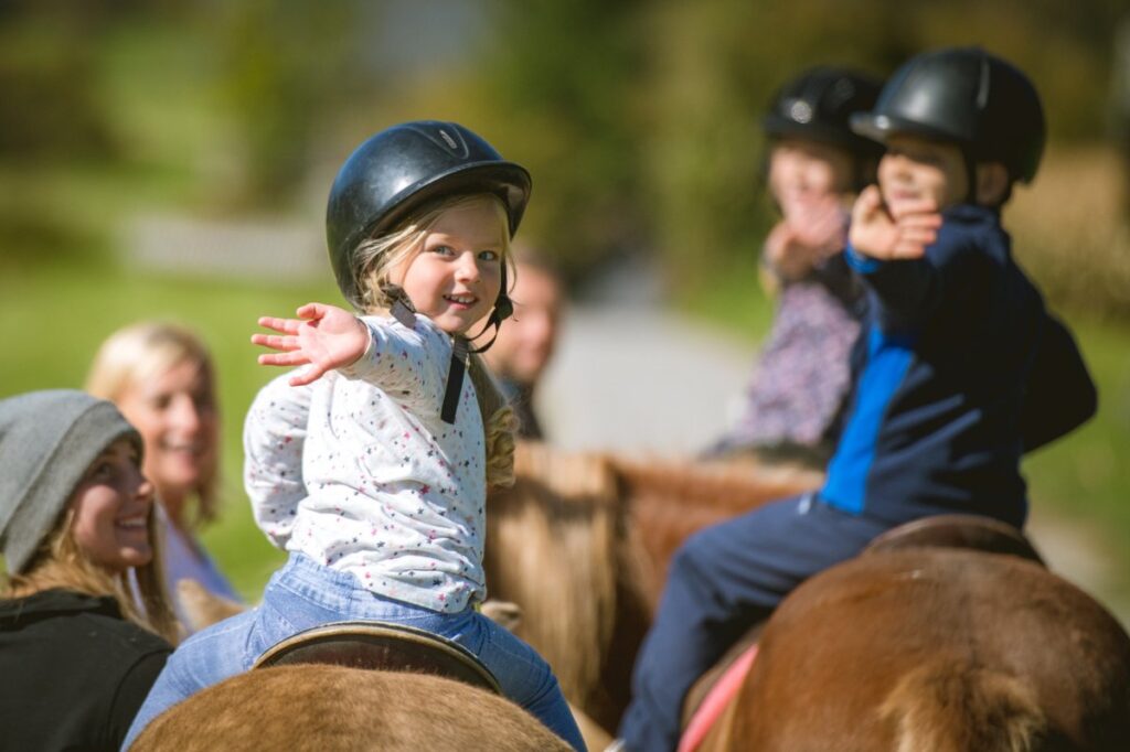 Kinder reiten fröhlich auf Ponys